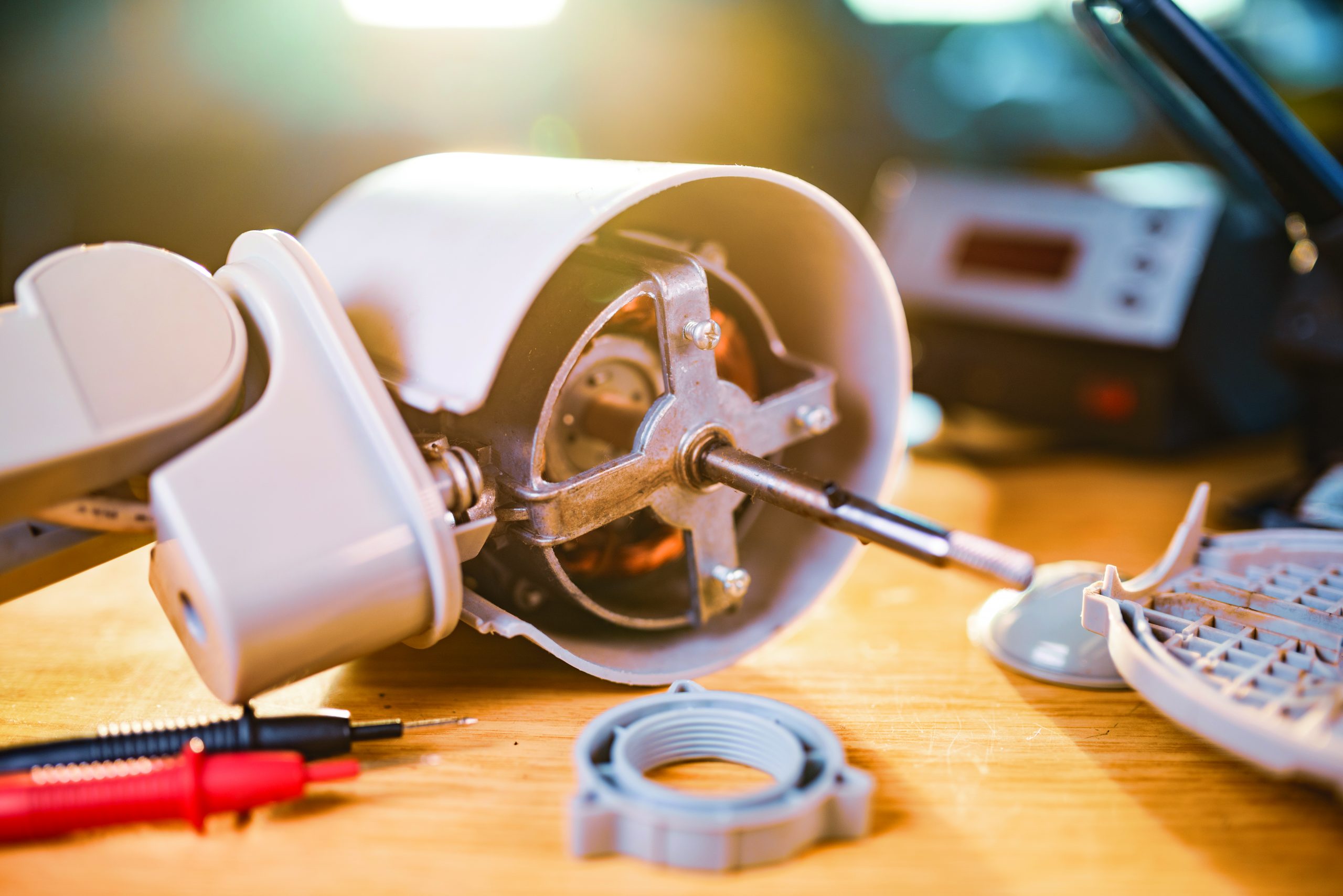 Close-up of an ironmotor from home cooling fan lies on a table during preventive cleaning, lubrication and repair in a specialized workshop. The concept of repair and restoration of damaged equipment