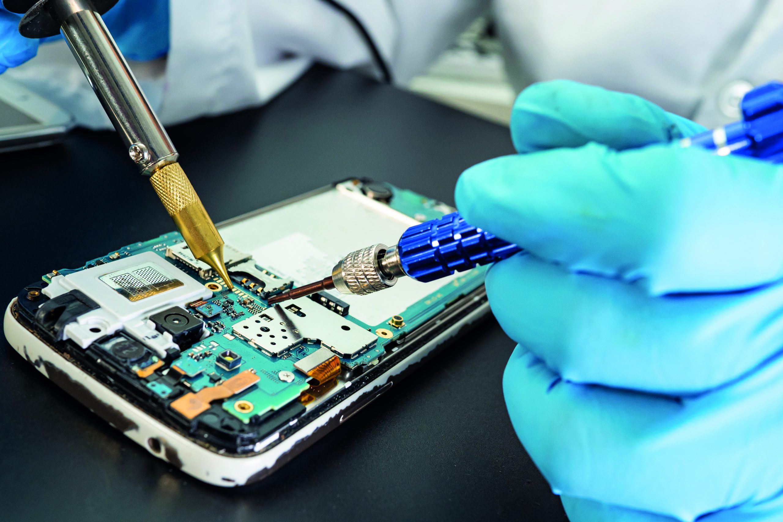 Technician repairing inside of mobile phone by soldering iron. Integrated Circuit. the concept of data, hardware, technology.